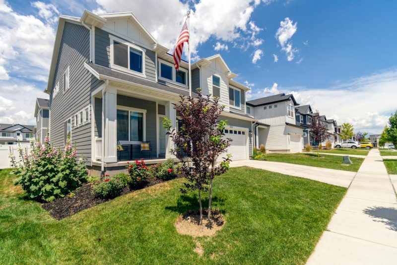 Modern suburban house with manicured garden and an American flag, featuring attractive architectural design.