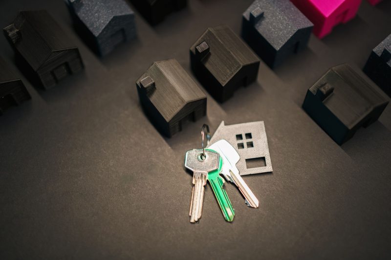Miniature house models alongside several keys representing real estate and home ownership.