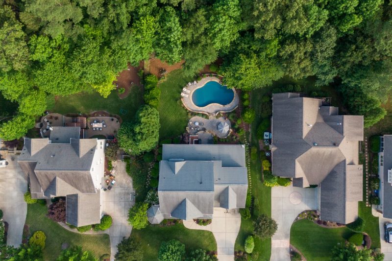Aerial view of a Wake Forest suburb featuring green backyards, houses, and a swimming pool.