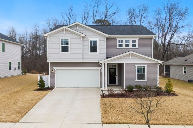 Charming two-story suburban home with a garage, surrounded by greenery in Fuquay-Varina, NC.