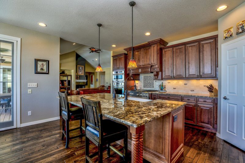 Stylish kitchen with a granite island, wooden cabinets, and modern appliances in a blend of rustic and contemporary design.