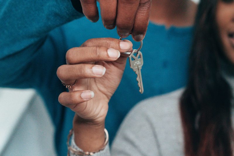 A couple holding a large house key, smiling and celebrating their new home.