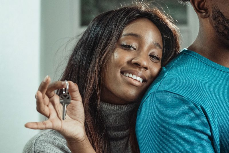 Joyful couple smiling and holding house keys outside their new home.